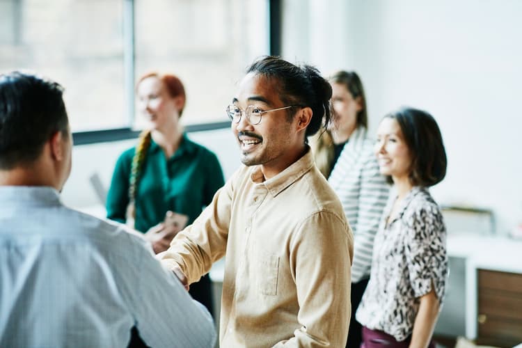 Businessman shaking hands with colleagues in a bright office
