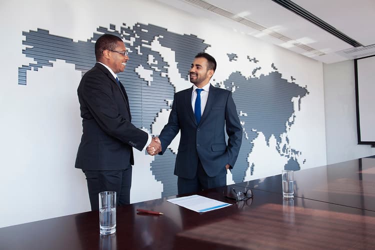 Businessmen shaking hands in front of a world map