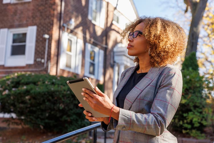 Real estate appraiser with clipboard outside a home