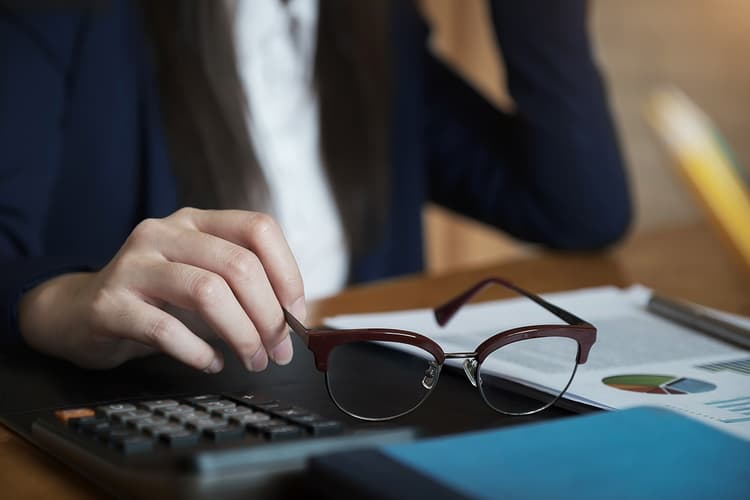 Woman in navy suit with glasses and calculator